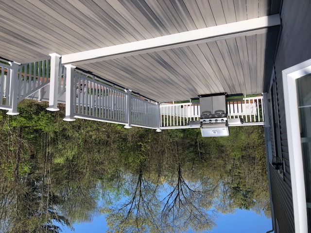 Composite deck with grill and white railing overlooking trees