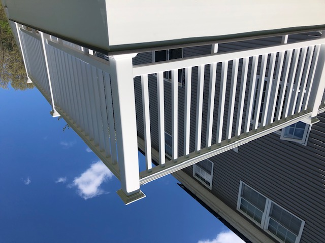 White vinyl deck railing detail against gray siding
